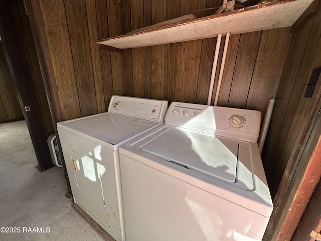 clothes washing area with wooden walls and washer and clothes dryer