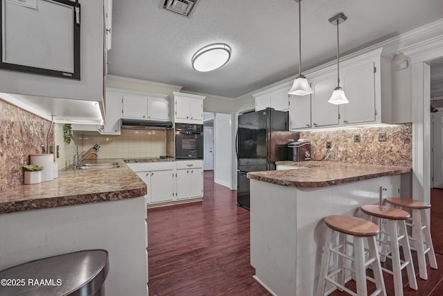 kitchen featuring hanging light fixtures, black appliances, white cabinets, a kitchen bar, and kitchen peninsula