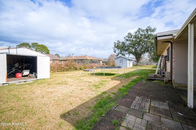 view of yard featuring a trampoline and a storage shed