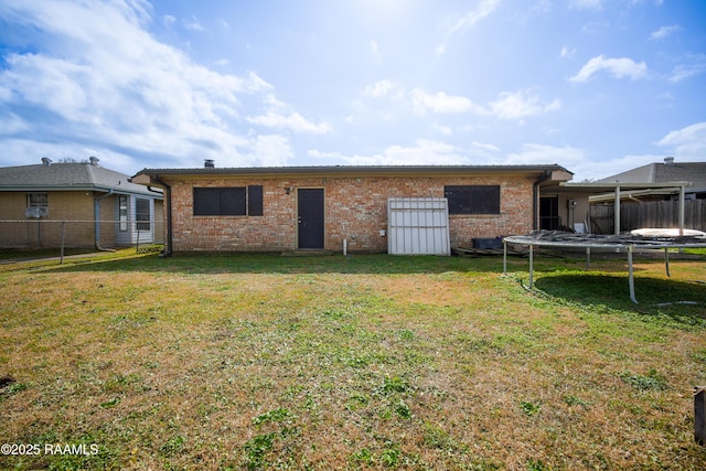 back of property featuring a yard and a trampoline