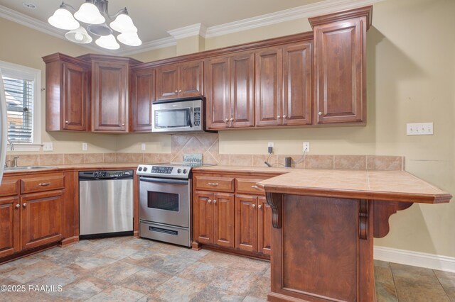 kitchen featuring an inviting chandelier, hanging light fixtures, crown molding, and stainless steel appliances