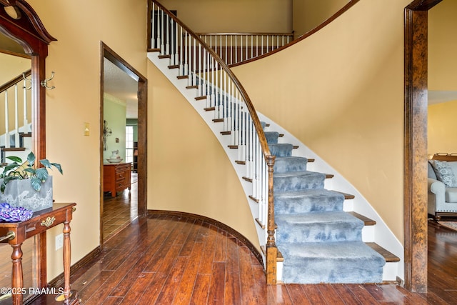 stairs featuring a towering ceiling and hardwood / wood-style floors