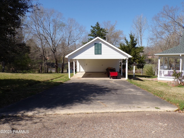 exterior space featuring aphalt driveway, covered porch, a lawn, and a carport