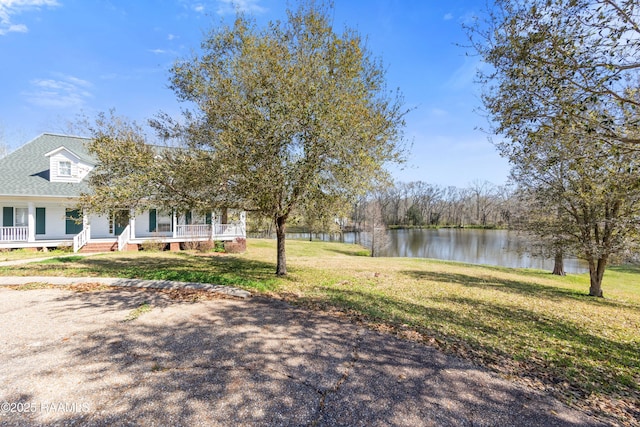 view of yard with a water view and covered porch