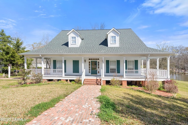 farmhouse featuring a porch, a front lawn, and roof with shingles