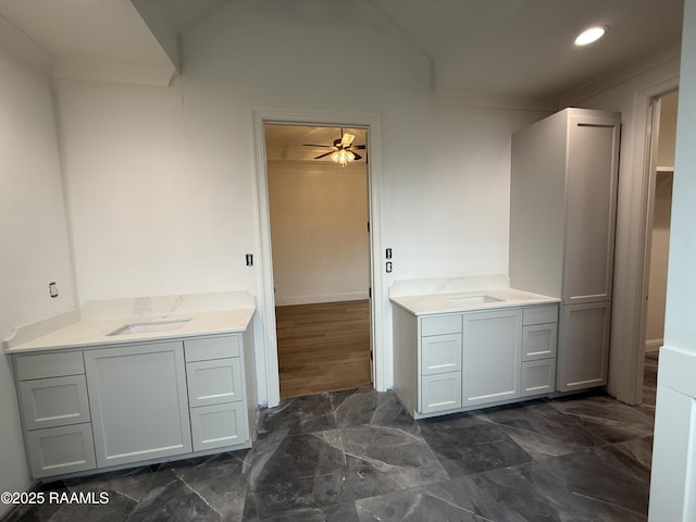 bathroom with ceiling fan, vanity, and vaulted ceiling