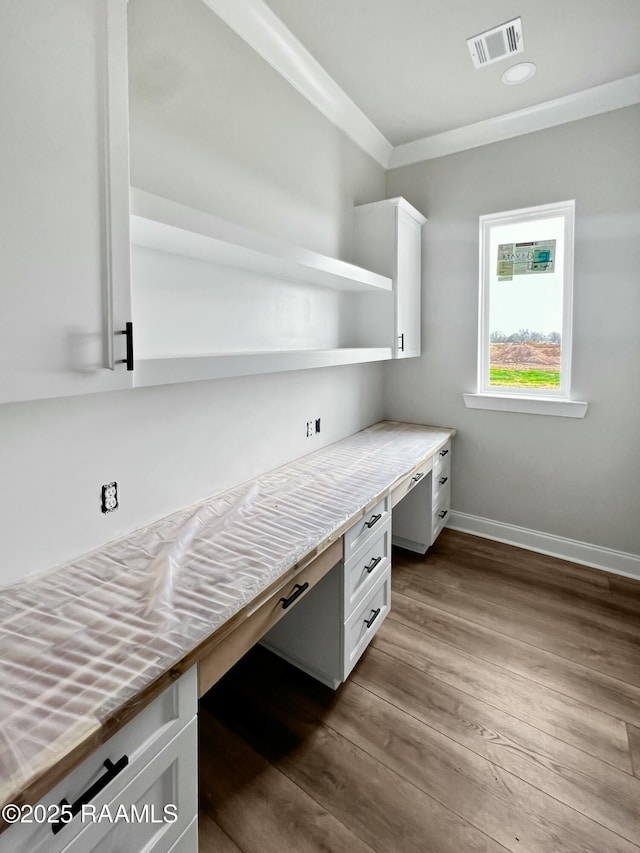 office featuring crown molding, built in desk, and light hardwood / wood-style flooring