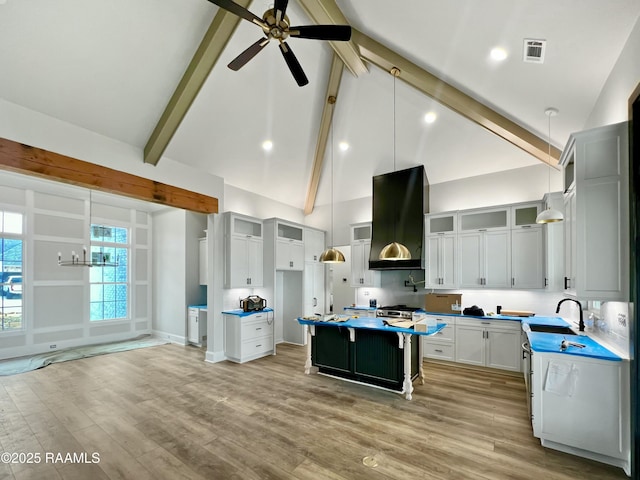 kitchen with sink, extractor fan, white cabinetry, a kitchen island, and pendant lighting