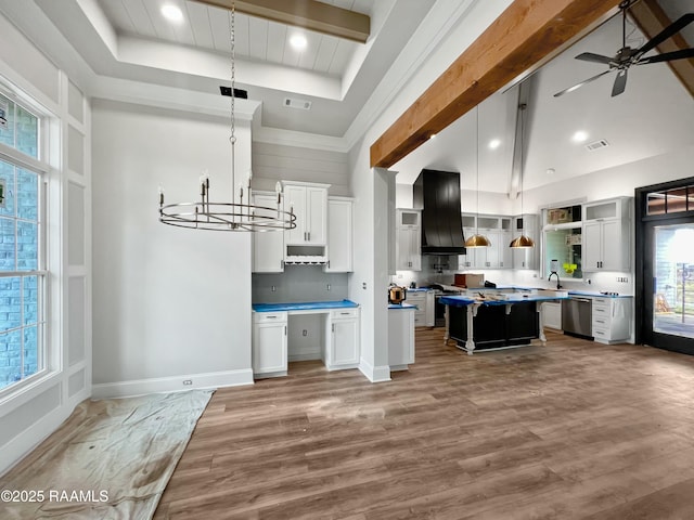 kitchen featuring white cabinetry, decorative light fixtures, custom exhaust hood, and a center island