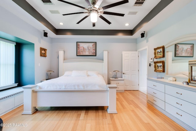 bedroom with light hardwood / wood-style floors and a raised ceiling