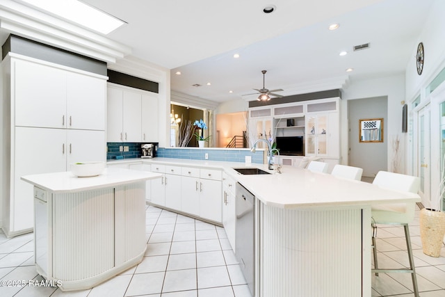 kitchen with sink, a breakfast bar, white cabinetry, a kitchen island, and kitchen peninsula