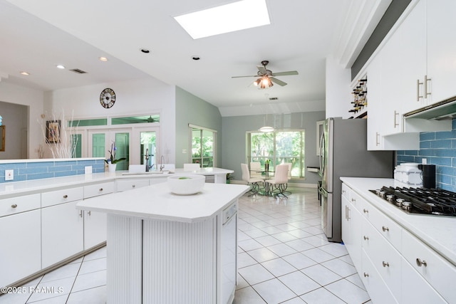 kitchen featuring white cabinetry, a skylight, light tile patterned floors, appliances with stainless steel finishes, and a kitchen island