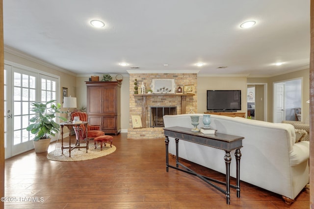 living room featuring hardwood / wood-style flooring, ornamental molding, and a fireplace