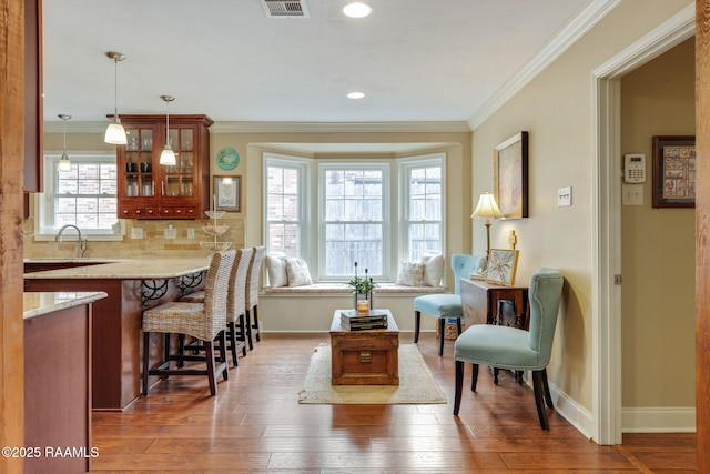 interior space featuring crown molding, dark hardwood / wood-style floors, pendant lighting, and a kitchen breakfast bar