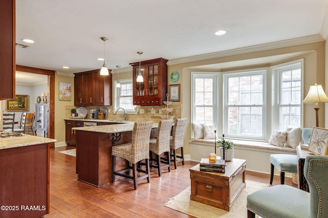 kitchen with sink, crown molding, tasteful backsplash, hardwood / wood-style flooring, and pendant lighting