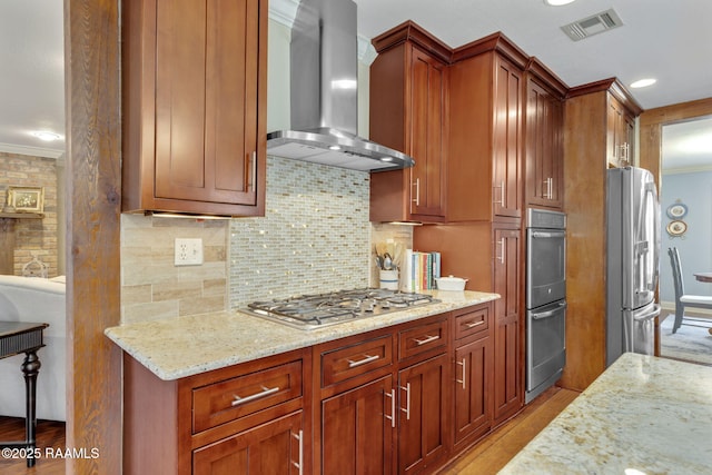 kitchen featuring appliances with stainless steel finishes, wall chimney exhaust hood, light stone countertops, and ornamental molding