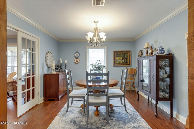 dining room featuring a notable chandelier, hardwood / wood-style flooring, ornamental molding, and french doors