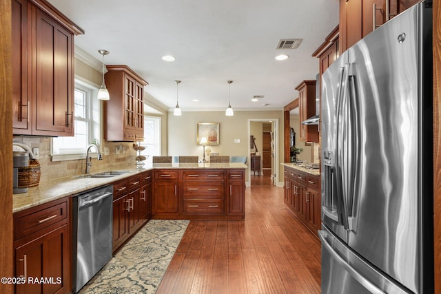 kitchen with sink, hanging light fixtures, ornamental molding, kitchen peninsula, and stainless steel appliances