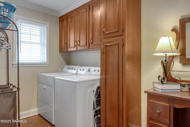 washroom with light hardwood / wood-style floors, ornamental molding, cabinets, and washing machine and clothes dryer