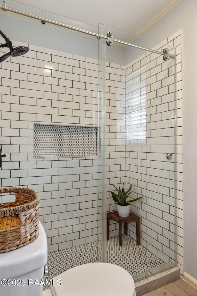 bathroom with ornamental molding, an enclosed shower, and toilet