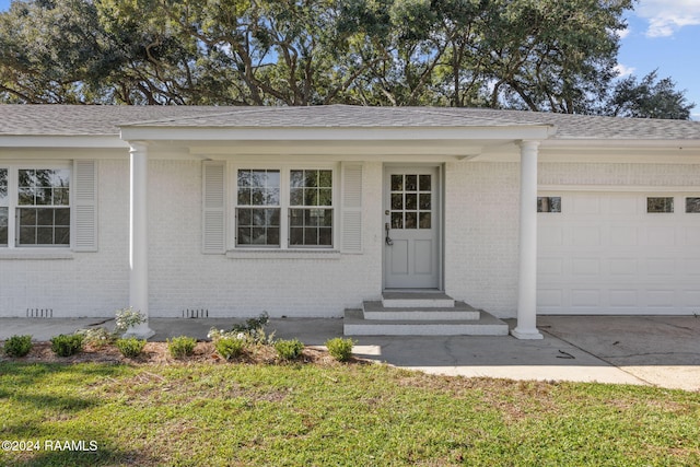 view of exterior entry with a garage and a lawn