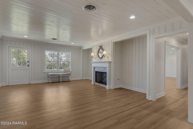 unfurnished living room with a premium fireplace, hardwood / wood-style floors, wood ceiling, and crown molding