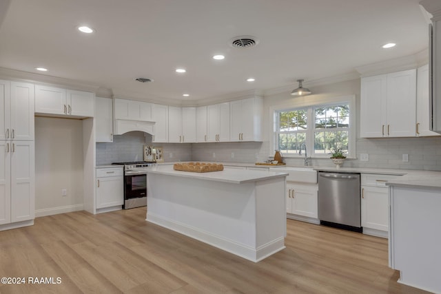 kitchen with sink, light wood-type flooring, white cabinets, and appliances with stainless steel finishes