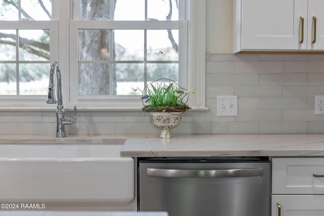 details featuring light stone counters, stainless steel dishwasher, white cabinetry, and sink