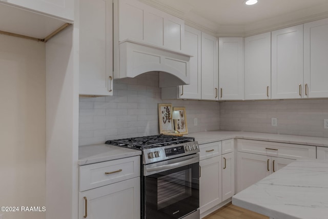 kitchen featuring gas stove, light stone countertops, white cabinets, and decorative backsplash