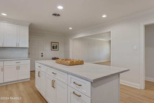 kitchen featuring crown molding, a kitchen island, white cabinets, and light wood-type flooring