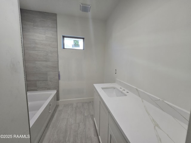 bathroom with hardwood / wood-style floors, vanity, and a bath