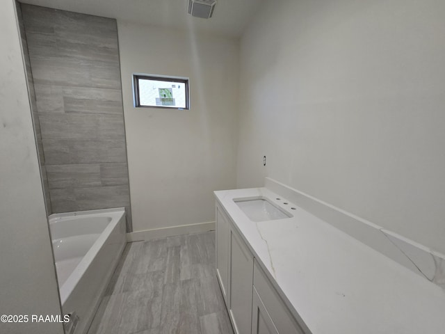 bathroom featuring vanity, hardwood / wood-style floors, and a tub to relax in