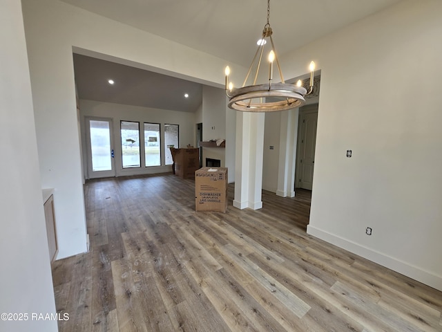 unfurnished dining area featuring hardwood / wood-style flooring, vaulted ceiling, and a notable chandelier