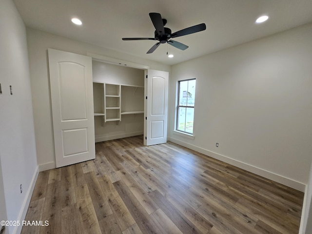 unfurnished bedroom with a spacious closet, light hardwood / wood-style flooring, a closet, and ceiling fan