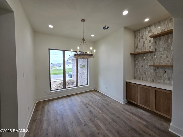 unfurnished dining area with dark wood-type flooring, recessed lighting, visible vents, and a notable chandelier