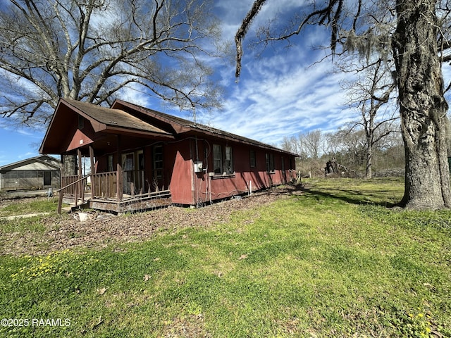 view of side of home with covered porch and a yard