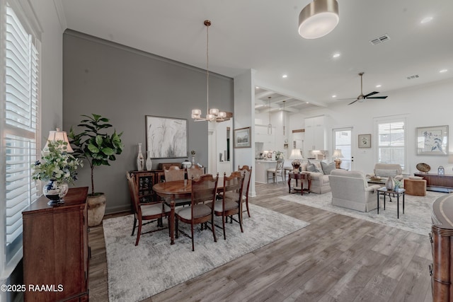 dining room with ceiling fan with notable chandelier, ornamental molding, and light hardwood / wood-style floors