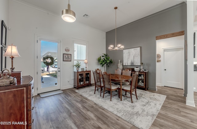 dining room featuring ornamental molding, light hardwood / wood-style floors, and a notable chandelier