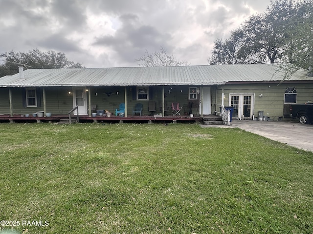 rear view of property with french doors, a lawn, and covered porch