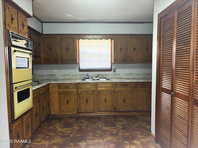 kitchen featuring ornamental molding, double wall oven, sink, and black gas cooktop