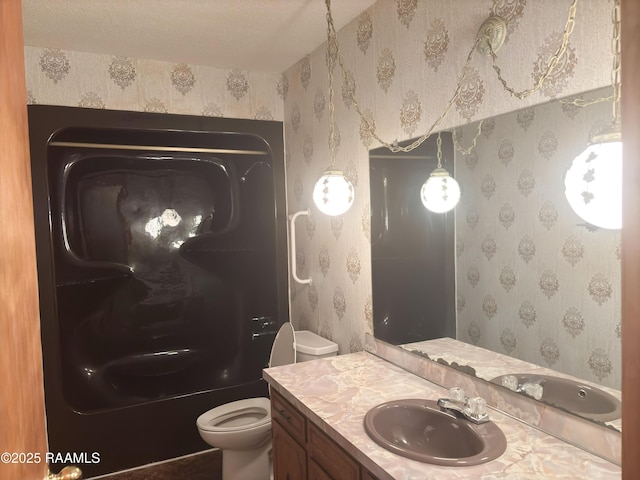 bathroom with vanity, toilet, and a textured ceiling