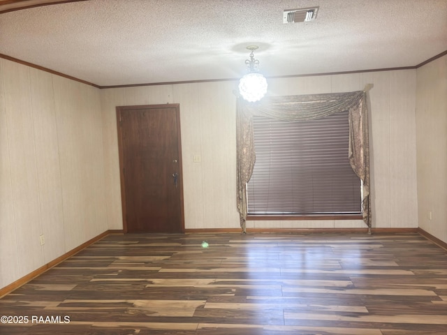 spare room featuring crown molding, a textured ceiling, and dark hardwood / wood-style flooring