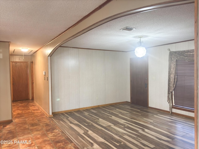 spare room featuring crown molding, dark hardwood / wood-style floors, and a textured ceiling