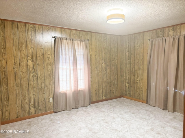 spare room with a textured ceiling and wood walls