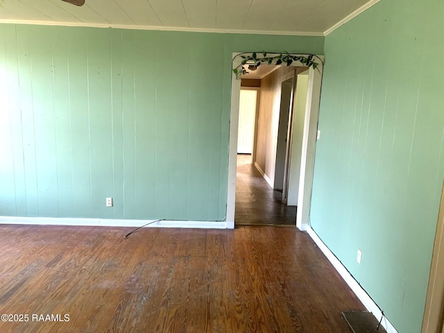 spare room with crown molding and dark wood-type flooring