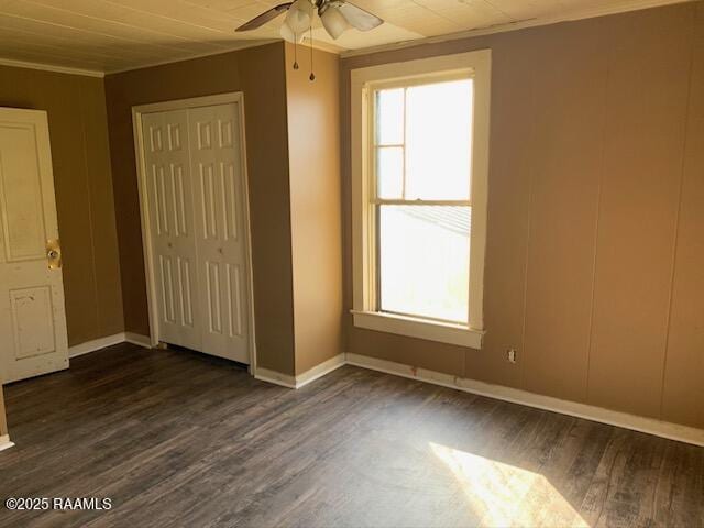 unfurnished bedroom featuring dark wood-type flooring, ceiling fan, ornamental molding, and a closet