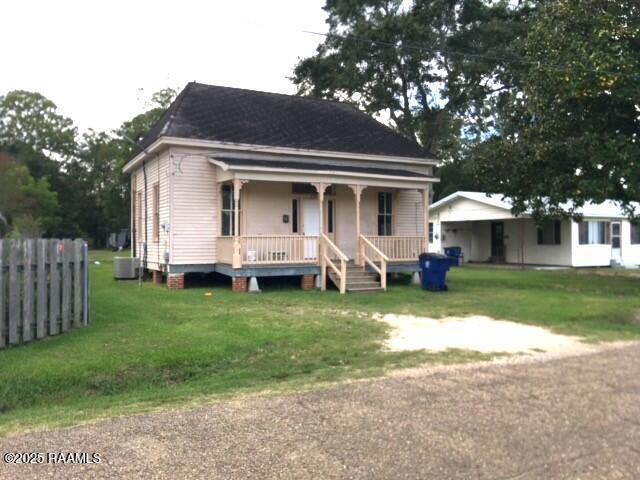 view of front of house featuring cooling unit, covered porch, and a front lawn