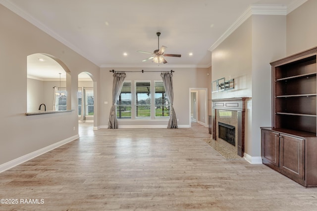 unfurnished living room with a fireplace, ornamental molding, ceiling fan, and light wood-type flooring