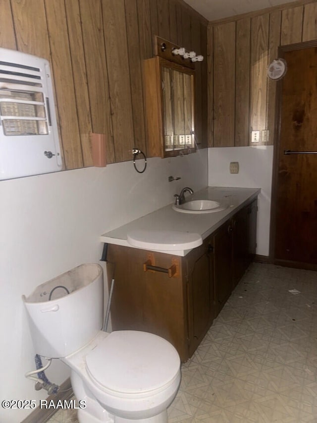 bathroom with vanity, toilet, and wood walls