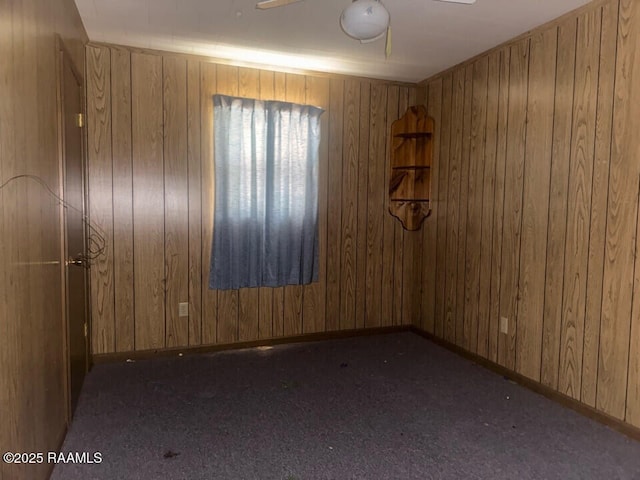 carpeted empty room featuring wooden walls